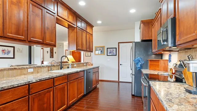 a kitchen with stainless steel appliances granite countertop a refrigerator a stove and a sink