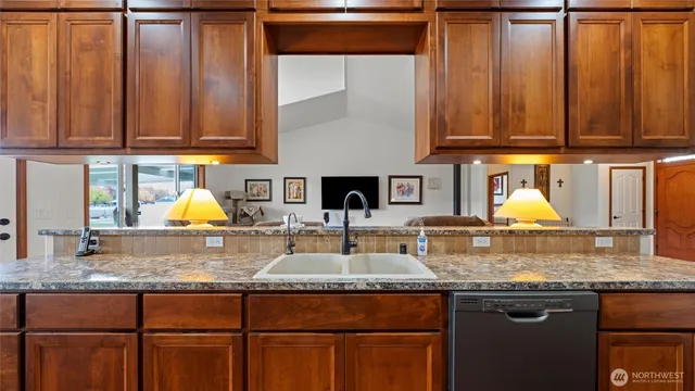a kitchen with granite countertop wooden cabinets a sink and dishwasher