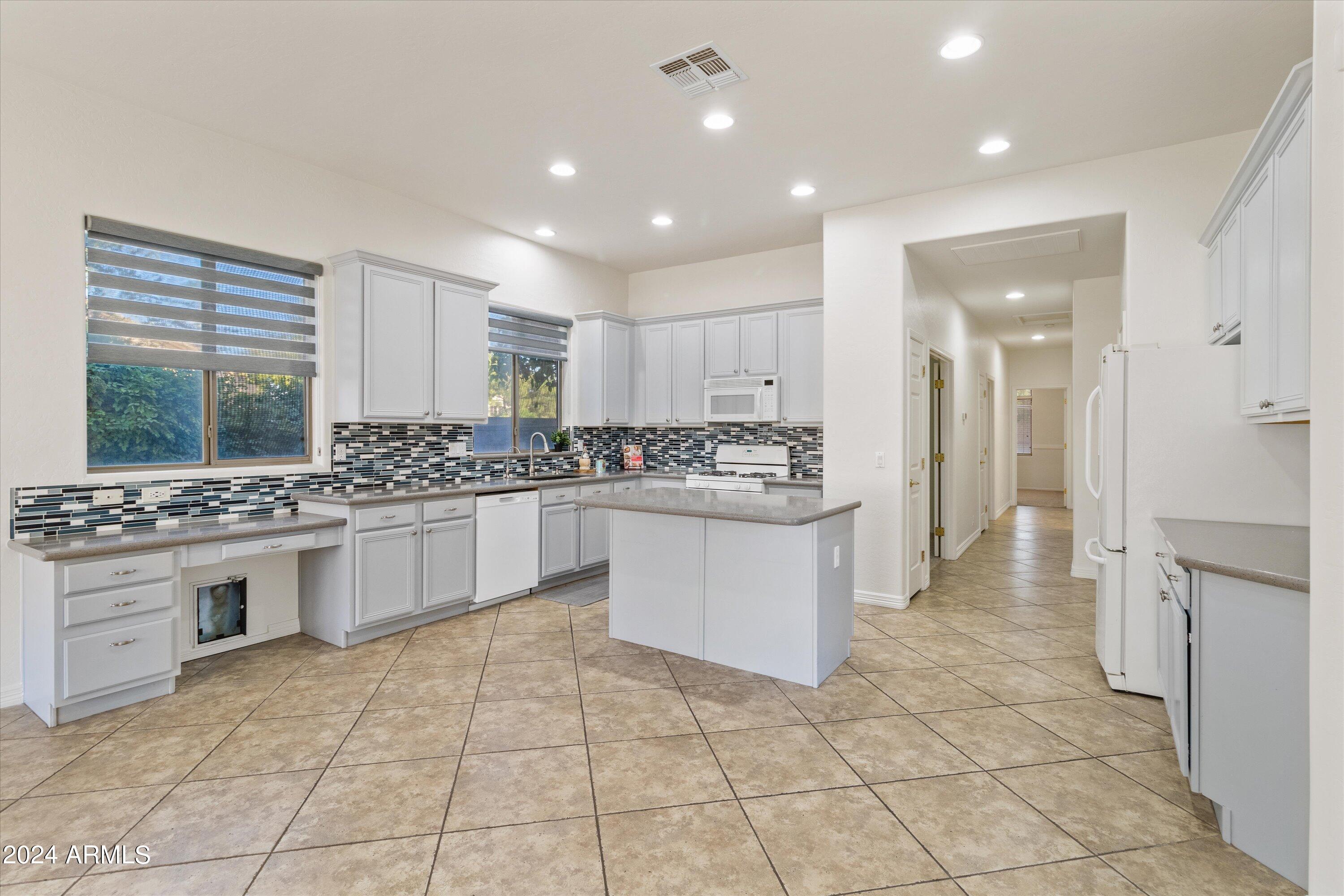 2860 East Nunneley Road Gilbert, AZ 85296 - Photo 13 of 28 a kitchen with a stove a sink dishwasher a refrigerator and white cabinets with wooden floor