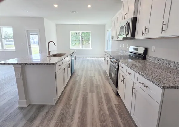 a spacious bathroom with a granite countertop sink a toilet a mirror and shower