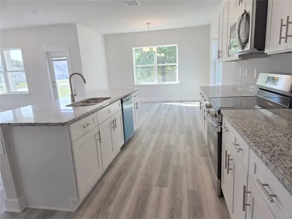 a kitchen with granite countertop a sink stove and cabinets