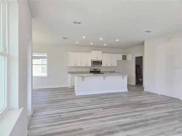 a view of kitchen with kitchen island stainless steel appliances wooden floor and window