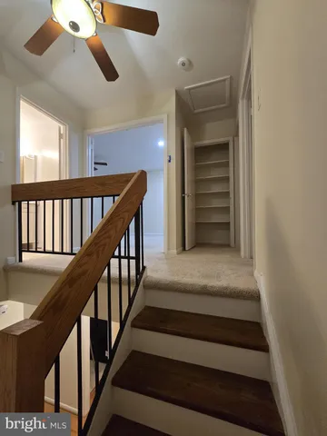 an empty room with wooden floor a ceiling fan and kitchen view
