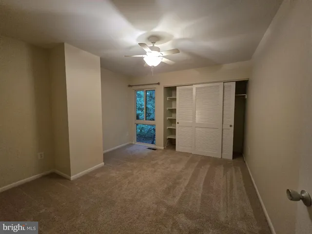 an empty room with wooden floor a ceiling fan and a window