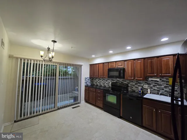 a kitchen with stainless steel appliances granite countertop wooden cabinets a stove and a sink