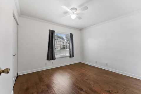 an empty room with wooden floor and fan