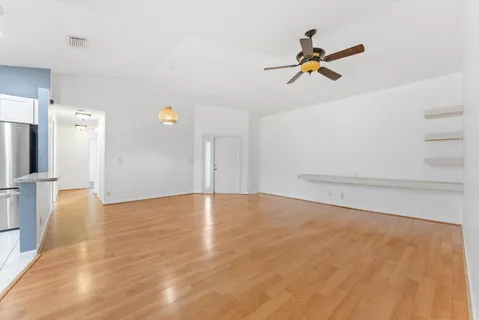 a view of empty room with wooden floor and ceiling fan