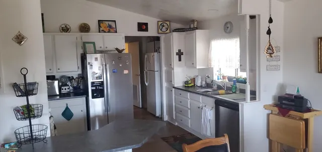 a kitchen with stainless steel appliances kitchen island granite countertop a refrigerator a stove and a sink with wooden floor