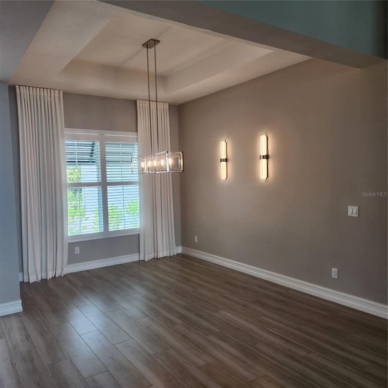 512 Blue Shell Loop Sarasota, FL 34240 - Photo 5 of 44 an empty room with wooden floor chandelier and windows
