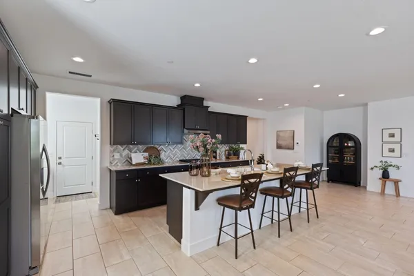 a kitchen with stainless steel appliances kitchen island granite countertop a table chairs sink and cabinets