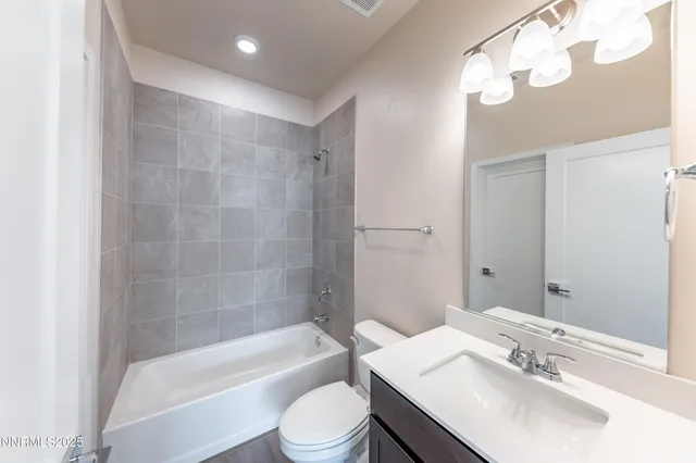 a bathroom with a bathtub shower sink vanity mirror and toilet