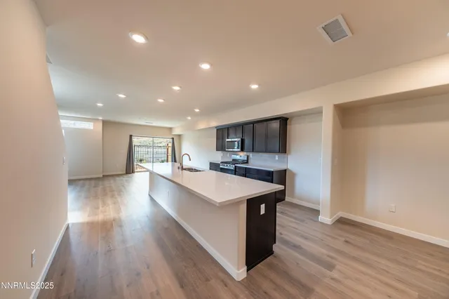 a large kitchen with stainless steel appliances granite countertop a large center island and a wooden floors