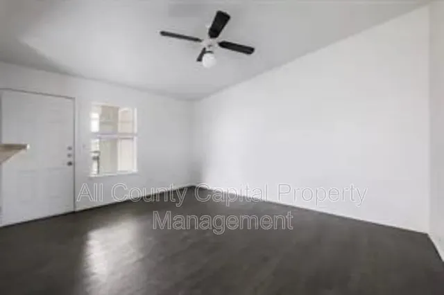 an empty room with wooden floor cabinet and windows
