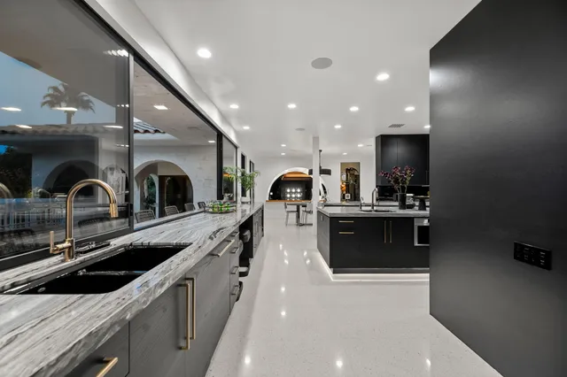 a view of a dining room with furniture a chandelier and kitchen view