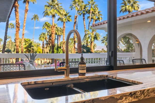 a view of a patio with dining table and chairs under an umbrella with a fire pit