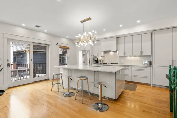 a kitchen with stainless steel appliances granite countertop a stove top oven a sink dishwasher and a dining table with wooden floor