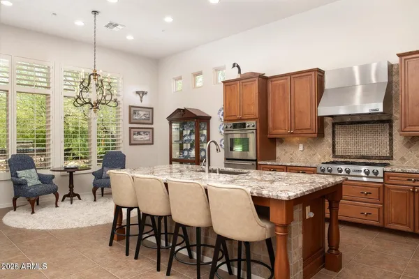 a kitchen with stainless steel appliances granite countertop a stove a refrigerator a kitchen island a dining table and chairs with wooden floor