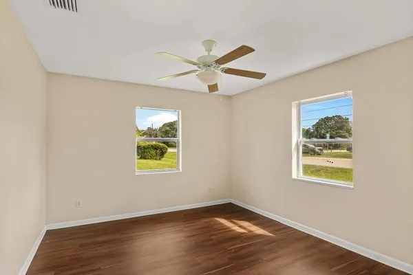 a view of an empty room with window and wooden floor