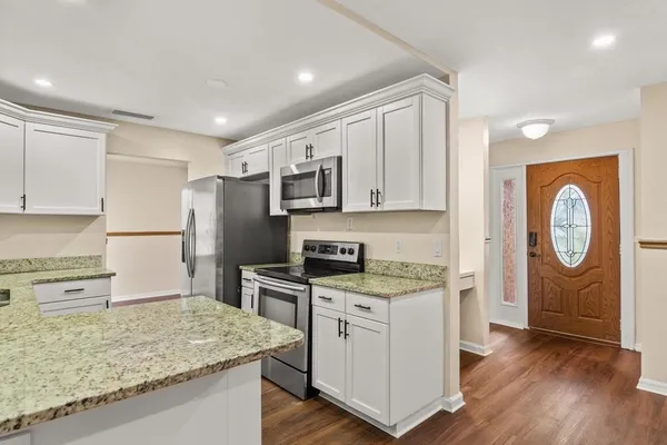a kitchen with stainless steel appliances granite countertop a refrigerator a stove top oven a sink and dishwasher with wooden floor
