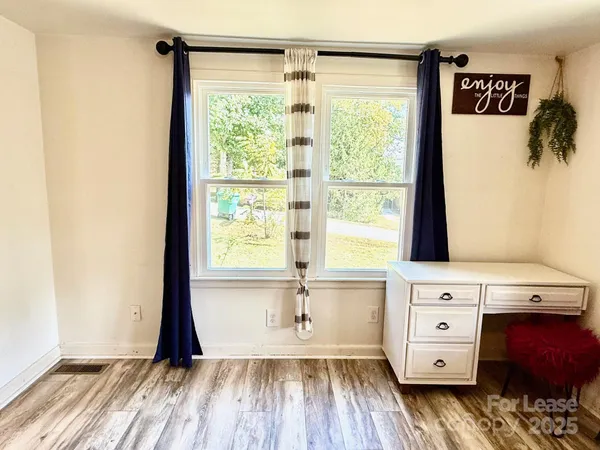 a view of an empty room with a window and wooden floor