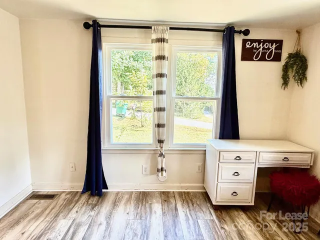 a view of an empty room with a window and wooden floor