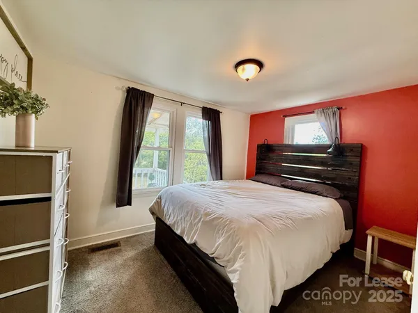 a bedroom with a bed dresser and a large window