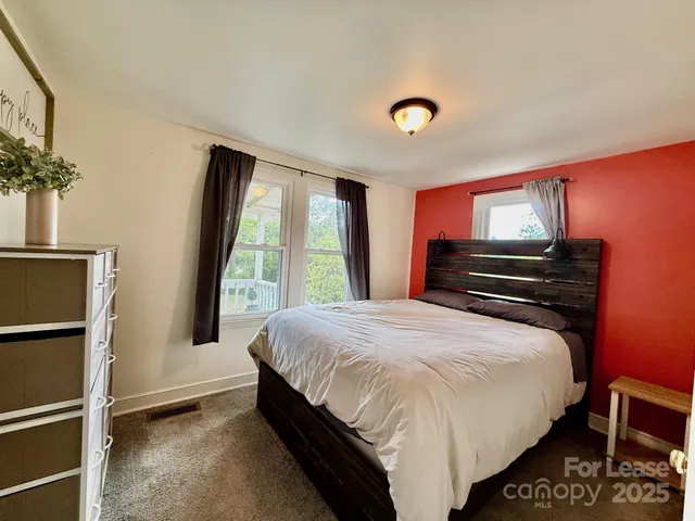 a bedroom with a bed dresser and a large window