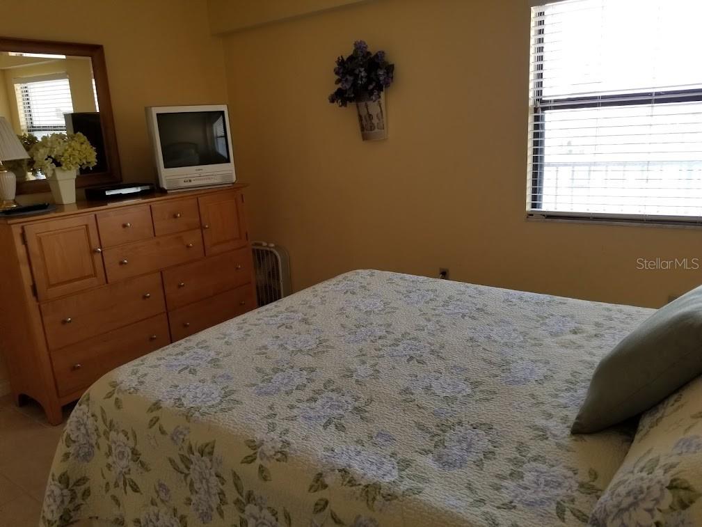 13650 Gulf Boulevard, Unit 304 Madeira Beach, FL 33708 - Photo 52 of 63 a bedroom with a bed and a flat screen tv