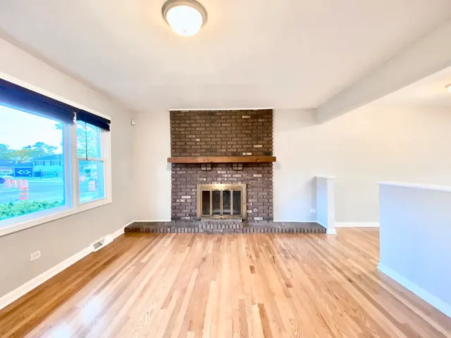 a view of empty room with wooden floor and fireplace