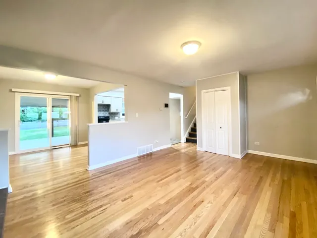 a view of empty room with wooden floor and windows