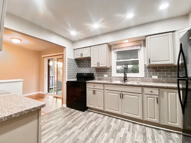 a kitchen with granite countertop a sink stove and refrigerator
