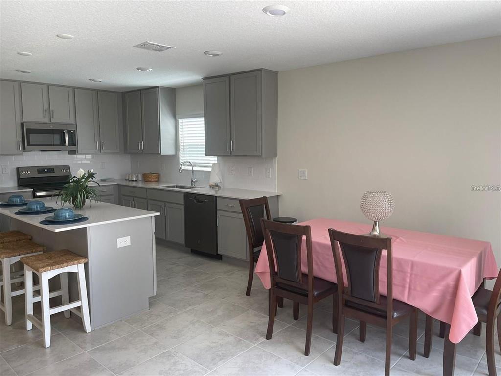4491 Magnolia Ridge Court Kissimmee, FL 34746 - Photo 5 of 21 a kitchen with a dining table chairs and a refrigerator