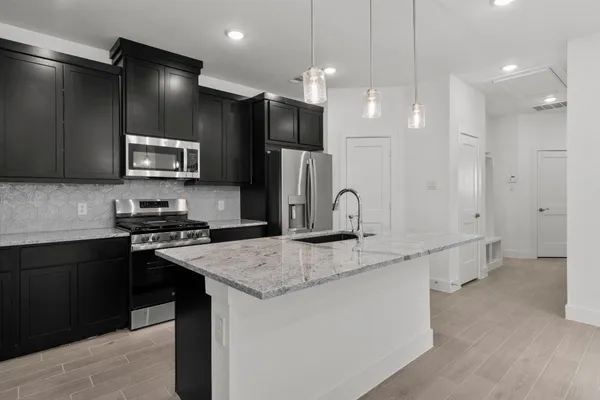 a kitchen with kitchen island a counter top space cabinets and stainless steel appliances