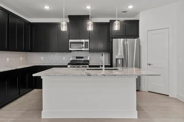 a kitchen with stainless steel appliances granite countertop a refrigerator and a stove top oven