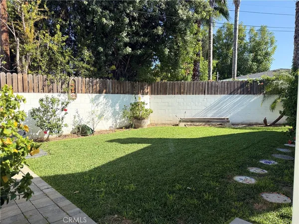 a view of a backyard with couches plants and large tree