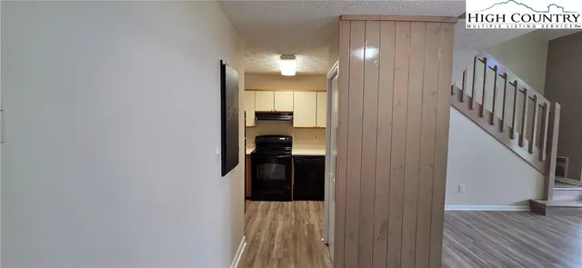 a view of hallway with wooden floor and a bathroom