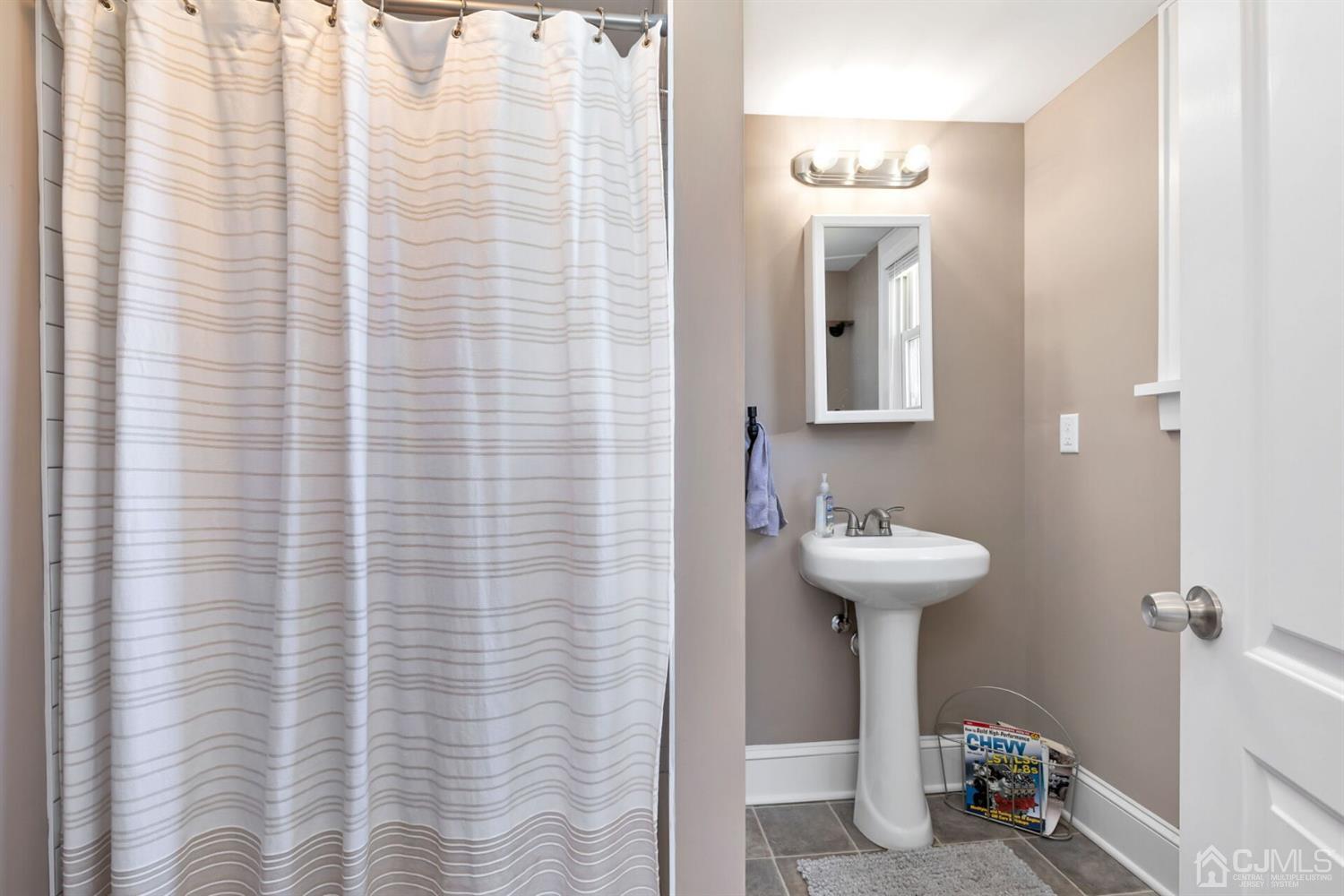 323 Washington Road Sayreville, NJ 08872 - Photo 21 of 40 a bathroom with a sink a mirror and a shower curtain