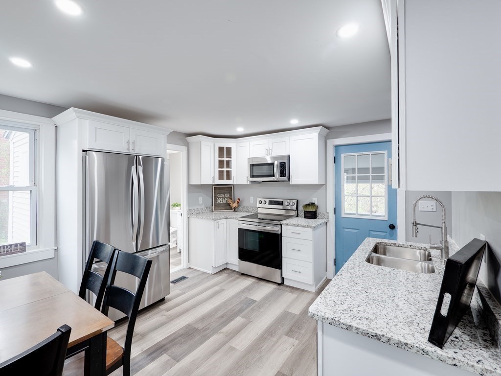 1104 Huntington Road Russell, MA 01071 - Photo 8 of 30 a kitchen with stainless steel appliances kitchen island granite countertop a refrigerator a stove a sink dishwasher and white cabinets with wooden floor
