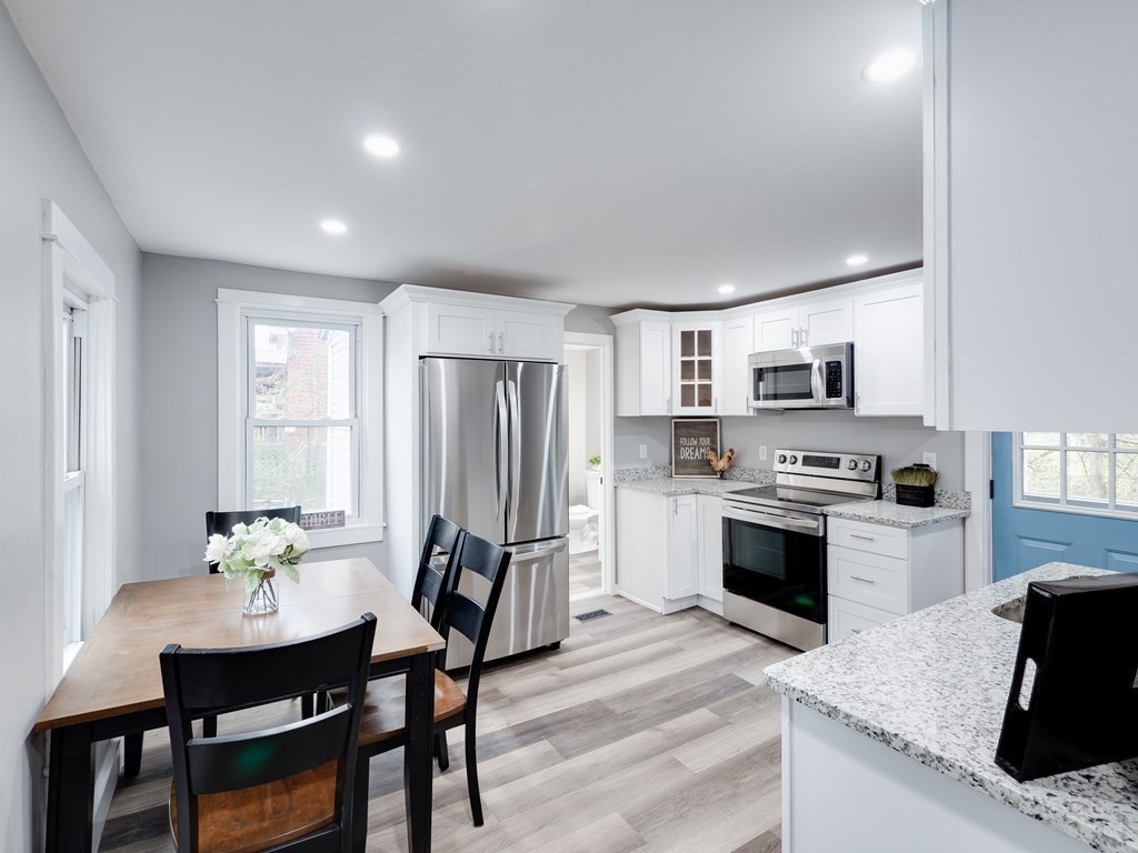1104 Huntington Road Russell, MA 01071 - Photo 10 of 30 a kitchen with stainless steel appliances granite countertop a stove top oven a refrigerator a sink dishwasher a dining table and chairs with wooden floor