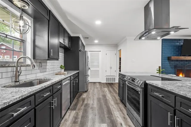 a kitchen with granite countertop stainless steel appliances a sink stove top oven and cabinets
