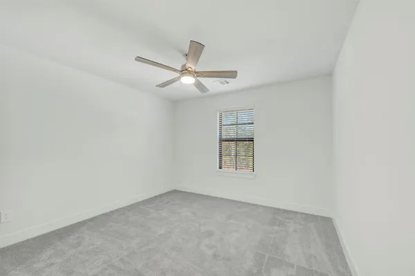 an empty room with wooden floor chandelier fan and windows