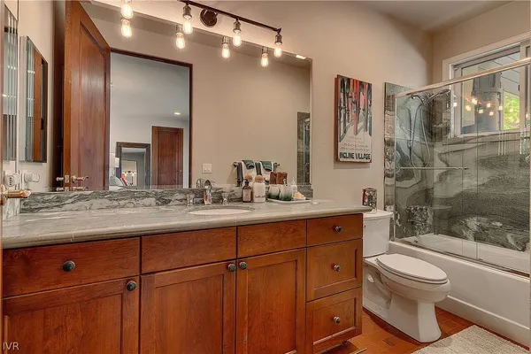 a spacious bathroom with a granite countertop sink a toilet and a mirror