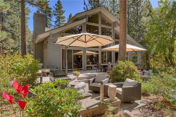 a view of a patio with couches table and chairs under an umbrella with a fire pit