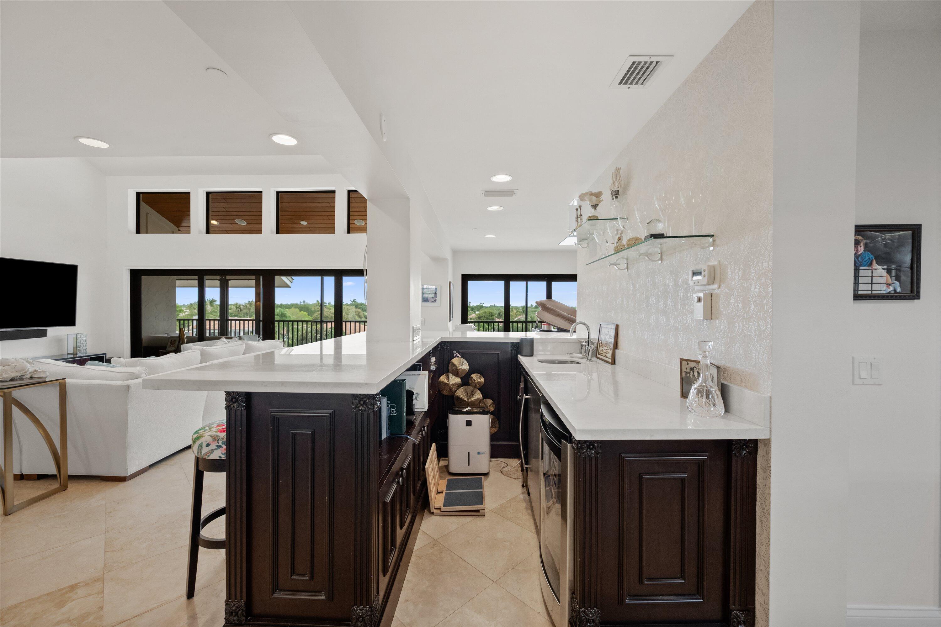 16910 Bay Street, Unit E 502 Jupiter, FL 33477 - Photo 19 of 43 a kitchen with a sink a stove and chairs