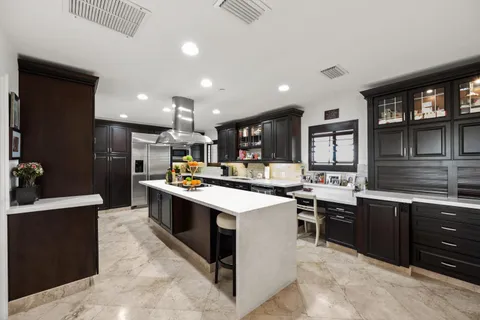 a kitchen with stainless steel appliances kitchen island granite countertop a sink and a refrigerator
