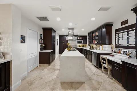 a large white kitchen with lots of counter space a sink appliances and cabinets