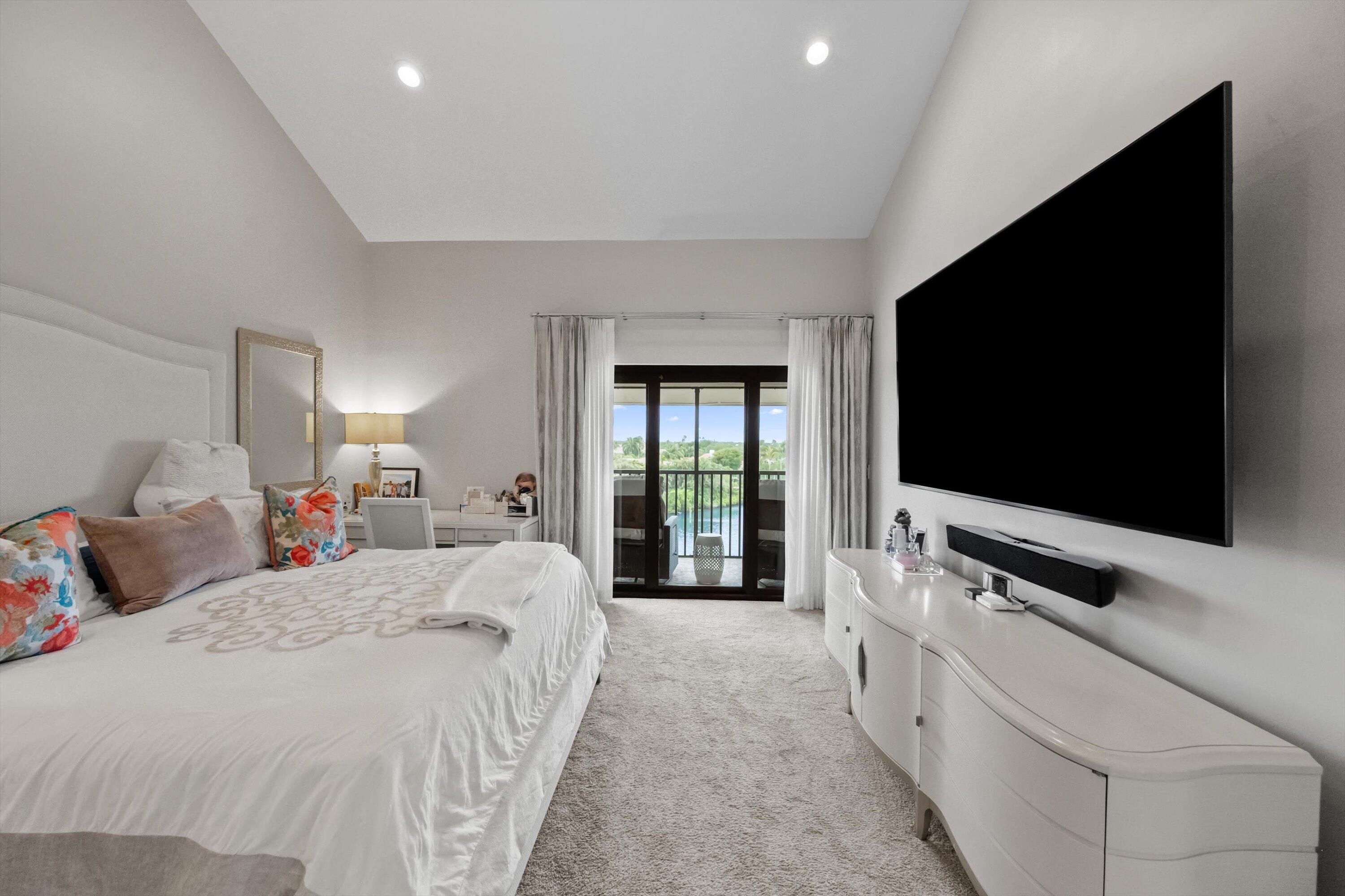 16910 Bay Street, Unit E 502 Jupiter, FL 33477 - Photo 34 of 43 a bedroom with a bed and a flat tv screen on wall
