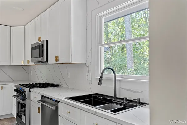 a kitchen with granite countertop a stove a sink and a microwave