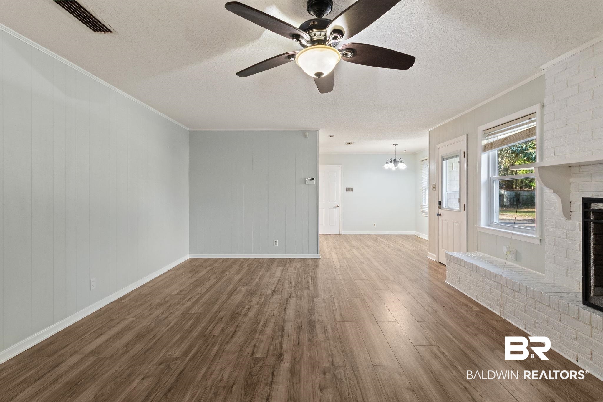 3864 Leroy Stevens Road Mobile, AL 36619 - Photo 7 of 33 Unfurnished living room with a fireplace, a textured ceiling, dark wood-style flooring, ceiling fan, and a chandelier
