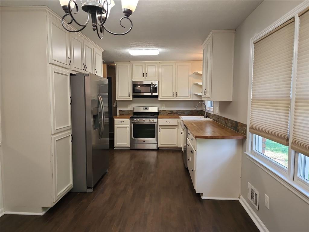 1476 Dupree Road Woodstock, GA 30189 - Photo 15 of 26 a kitchen with stainless steel appliances granite countertop a refrigerator a sink dishwasher a stove and a dining table with wooden floor